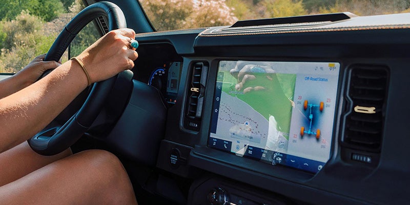 Hands on a steering wheel, in-car map display shows Las Vegas and Off-Road Status
