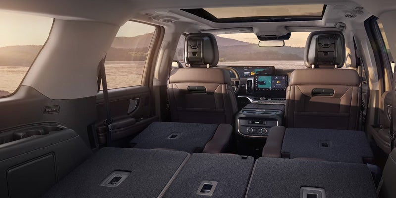 View from the car's interior, showing brown leather seats and the back two rows of seats folded flat.